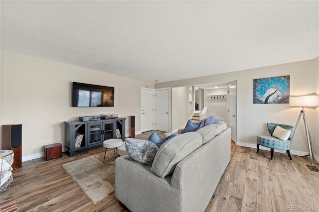 living room with light wood-style floors, baseboards, and stairs