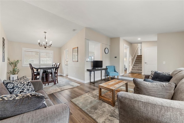 living room with baseboards, hardwood / wood-style flooring, stairway, an inviting chandelier, and vaulted ceiling