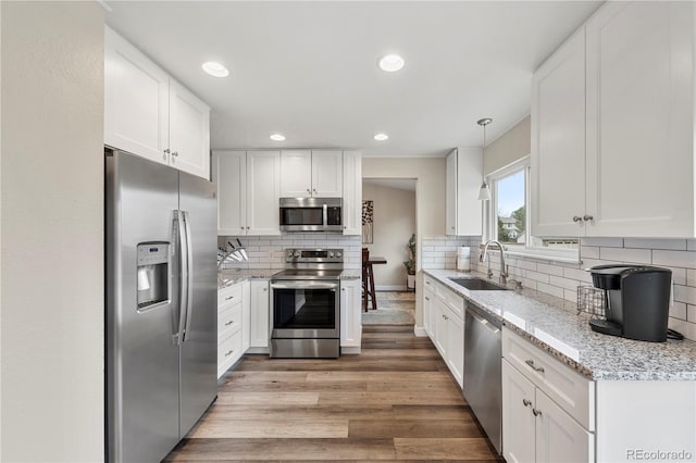 kitchen with light wood finished floors, white cabinetry, stainless steel appliances, and a sink