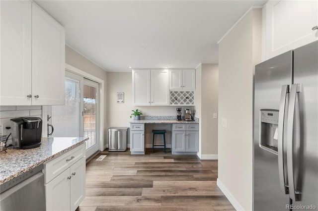 kitchen featuring dark wood-style floors, appliances with stainless steel finishes, backsplash, and white cabinets