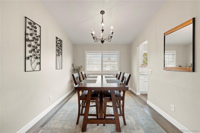 dining room with baseboards, wood finished floors, and a notable chandelier