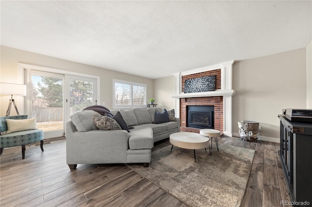 living area with a textured ceiling, a fireplace, dark wood finished floors, and baseboards