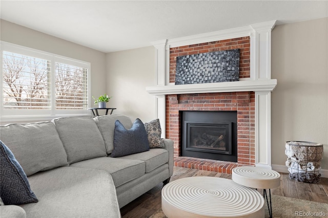 living area featuring a fireplace, baseboards, and wood finished floors