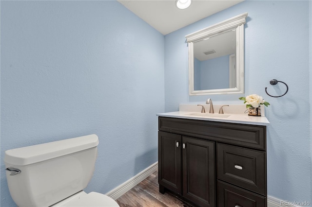 bathroom with baseboards, visible vents, toilet, wood finished floors, and vanity