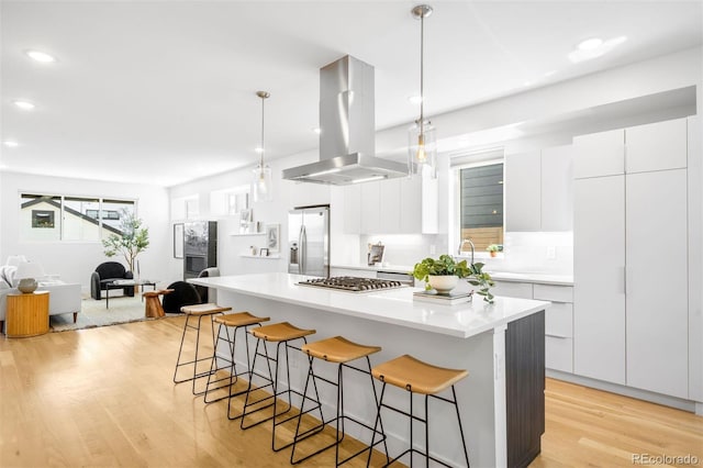 3658 Quivas St, Denver, CO 80211 - kitchen with island exhaust hood, stainless steel appliances, a breakfast bar area, modern cabinets, and light wood-style flooring