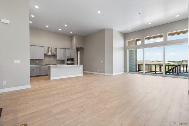 unfurnished living room featuring light hardwood / wood-style flooring and a high ceiling