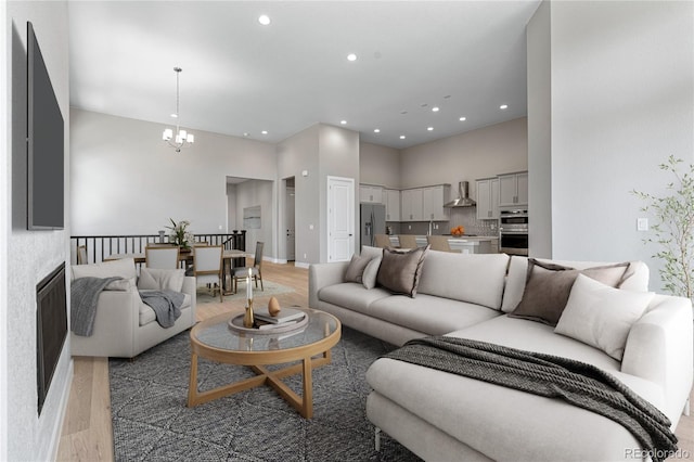 living room with a towering ceiling, a notable chandelier, and light hardwood / wood-style floors