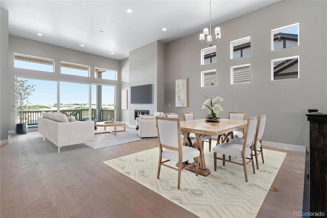 dining room featuring a towering ceiling, light hardwood / wood-style flooring, and a notable chandelier