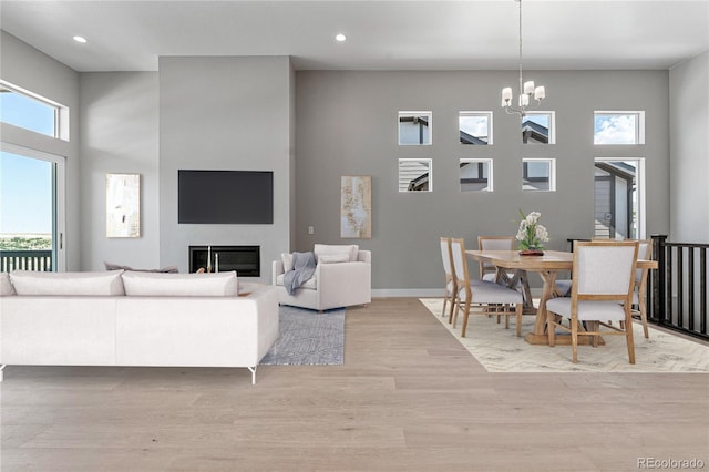 living room with light hardwood / wood-style floors, a high ceiling, and a notable chandelier