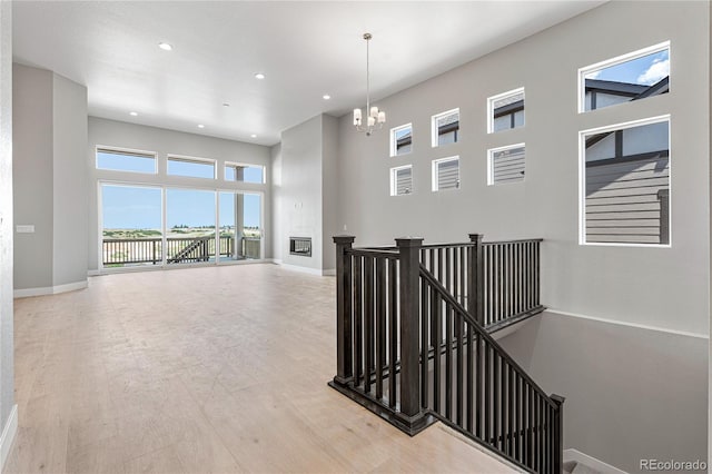 hallway featuring an inviting chandelier, hardwood / wood-style floors, and a high ceiling