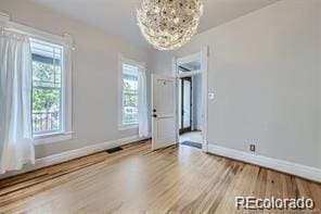 empty room with hardwood / wood-style floors and an inviting chandelier