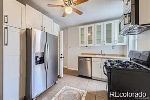 kitchen with appliances with stainless steel finishes, ceiling fan, white cabinets, and light tile patterned floors