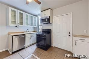 kitchen with stainless steel appliances, white cabinetry, ceiling fan, and light tile patterned floors