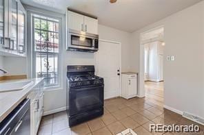 kitchen with dishwasher, white cabinetry, light tile patterned flooring, black gas range, and sink