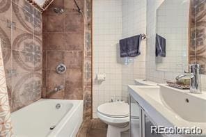 full bathroom featuring tile walls, toilet, vanity, and tiled shower / bath