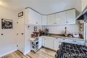 kitchen with light hardwood / wood-style floors, gas stove, and white cabinetry