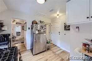 kitchen featuring lofted ceiling, white cabinets, stainless steel refrigerator, and light wood-type flooring