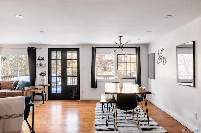 dining room featuring an inviting chandelier, light wood-type flooring, and french doors