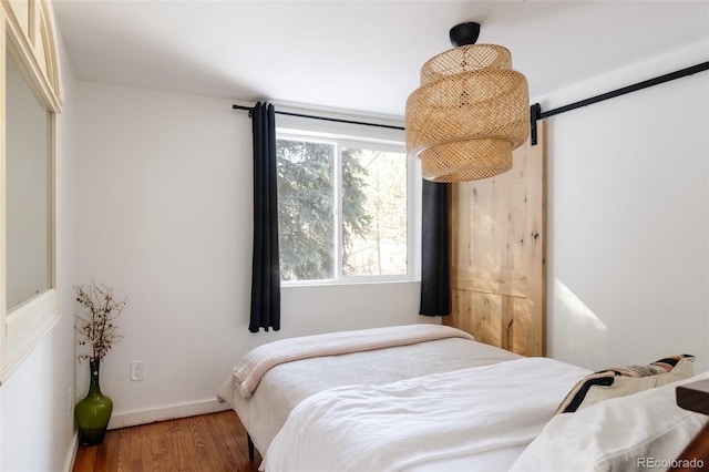 bedroom featuring a barn door and hardwood / wood-style floors