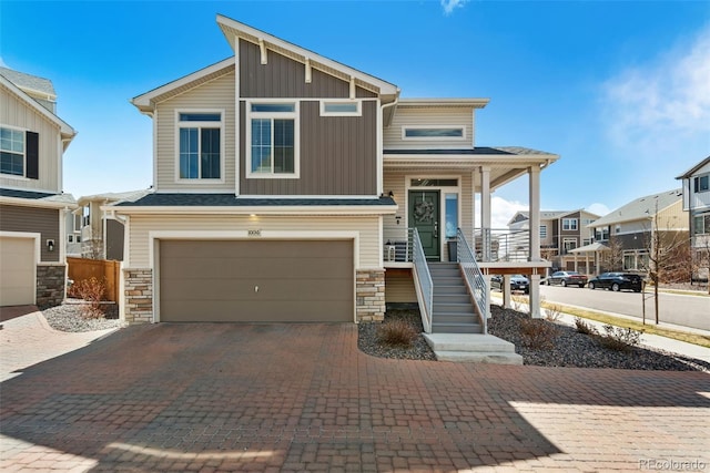 view of front of house with board and batten siding, a garage, stone siding, and stairs