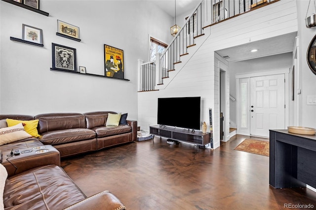 living area with stairway, a high ceiling, and concrete flooring