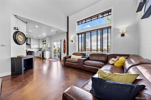 living room with recessed lighting, a high ceiling, plenty of natural light, and baseboards