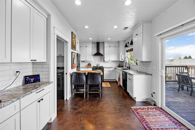 kitchen featuring black appliances, recessed lighting, a sink, and wall chimney exhaust hood