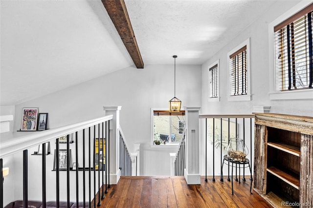 corridor featuring vaulted ceiling with beams, a chandelier, an upstairs landing, and wood finished floors