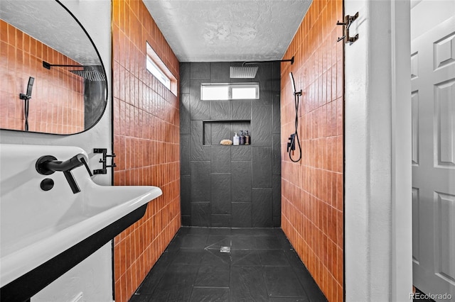 bathroom featuring a textured ceiling, tile patterned floors, tile walls, and a tile shower