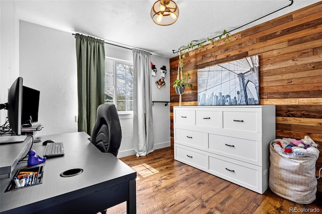 home office featuring baseboards, wood walls, and wood finished floors