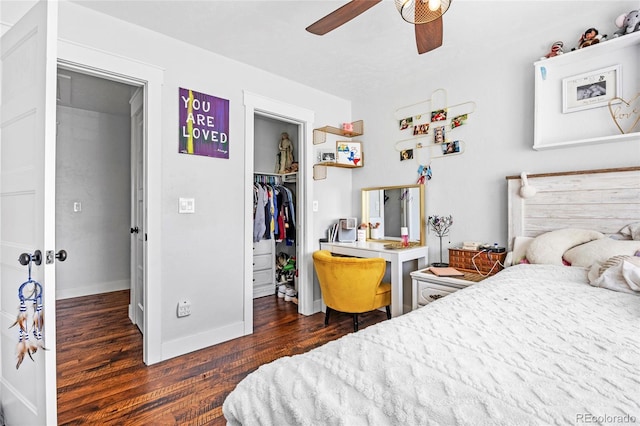 bedroom with ceiling fan, a walk in closet, baseboards, wood finished floors, and a closet