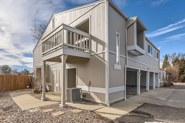 view of side of property featuring cooling unit, a balcony, and a garage