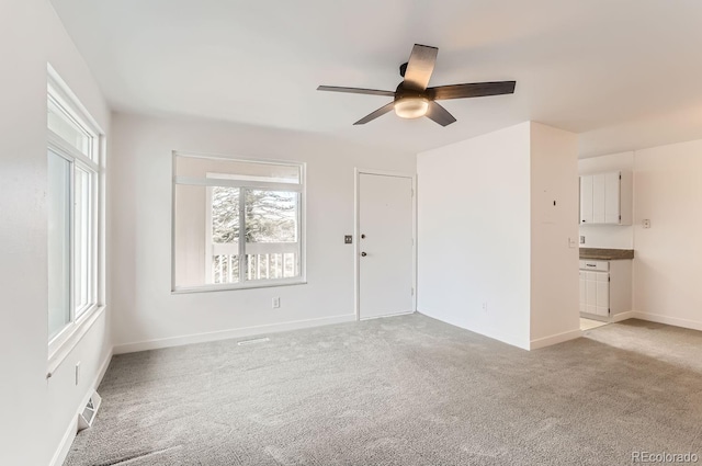 empty room with ceiling fan and light carpet