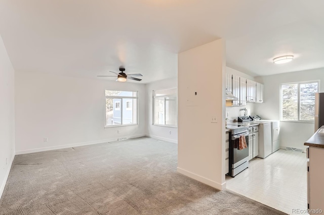 kitchen with white cabinetry, plenty of natural light, light carpet, washer / dryer, and stainless steel electric stove