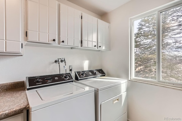 clothes washing area featuring cabinets and washing machine and clothes dryer