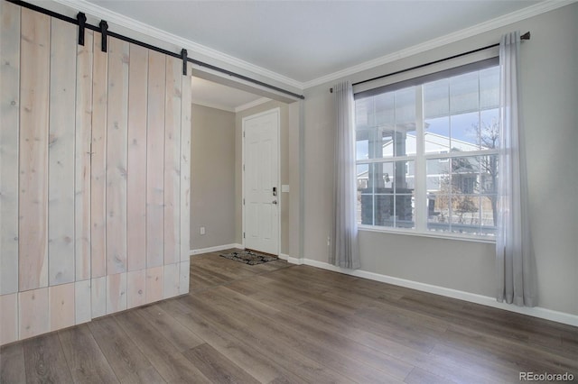 unfurnished room featuring crown molding, wood-type flooring, and a barn door