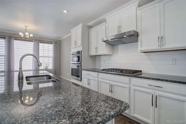 kitchen with sink, crown molding, dark stone countertops, appliances with stainless steel finishes, and white cabinets