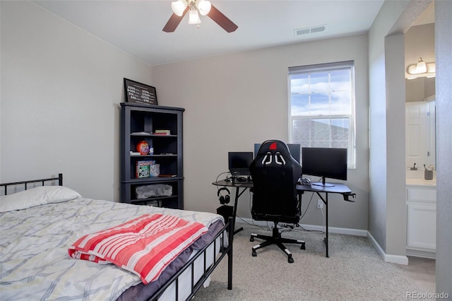 bedroom featuring ceiling fan, light colored carpet, and ensuite bath