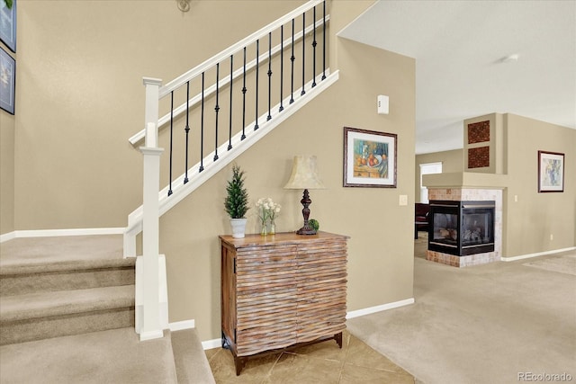 stairs featuring baseboards, carpet floors, and a fireplace