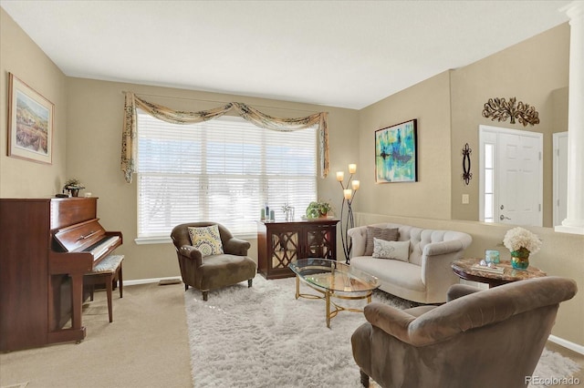 living area featuring ornate columns, baseboards, a wealth of natural light, and carpet floors