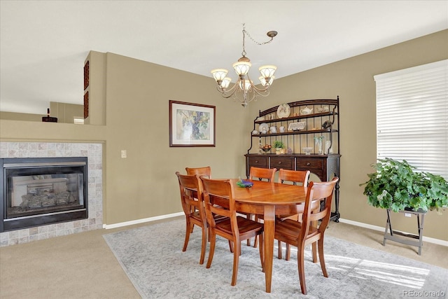 carpeted dining room with a chandelier, a tile fireplace, and baseboards