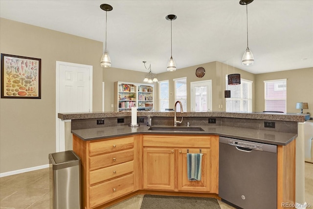 kitchen with dark countertops, a healthy amount of sunlight, dishwasher, and a sink