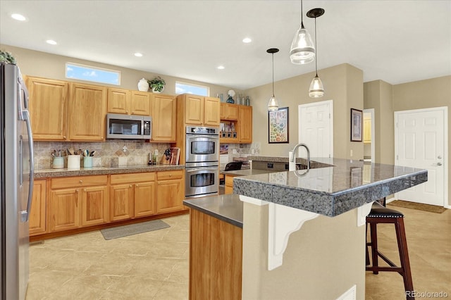 kitchen featuring recessed lighting, hanging light fixtures, appliances with stainless steel finishes, a kitchen breakfast bar, and backsplash