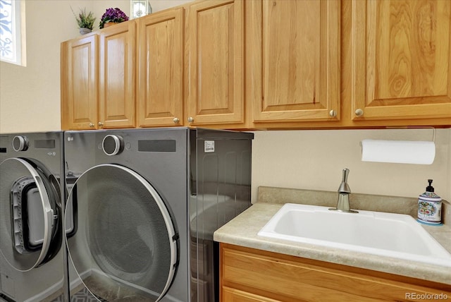 washroom featuring washing machine and dryer, cabinet space, and a sink