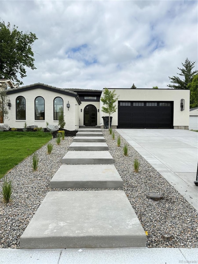 3065 S Birch St, Denver, CO 80222 - mediterranean / spanish-style house featuring an attached garage, concrete driveway, a front lawn, and stucco siding
