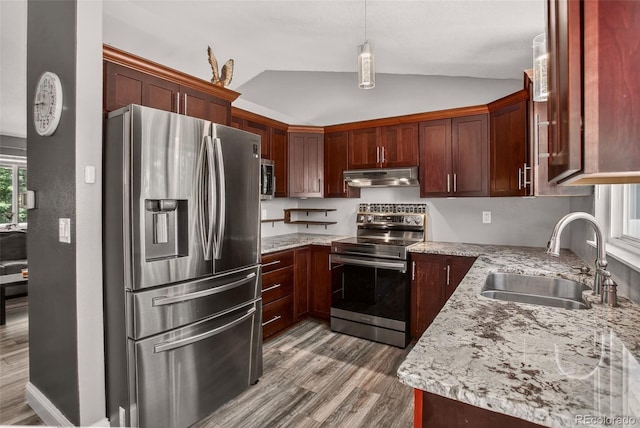 6034 S Parfet St, Littleton, CO 80127 - kitchen featuring appliances with stainless steel finishes, under cabinet range hood, vaulted ceiling, wood finished floors, and light stone countertops