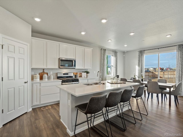 kitchen featuring a center island with sink, sink, white cabinetry, appliances with stainless steel finishes, and dark hardwood / wood-style flooring