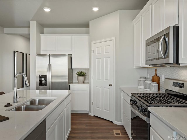 kitchen featuring white cabinetry, appliances with stainless steel finishes, dark hardwood / wood-style floors, light stone counters, and sink