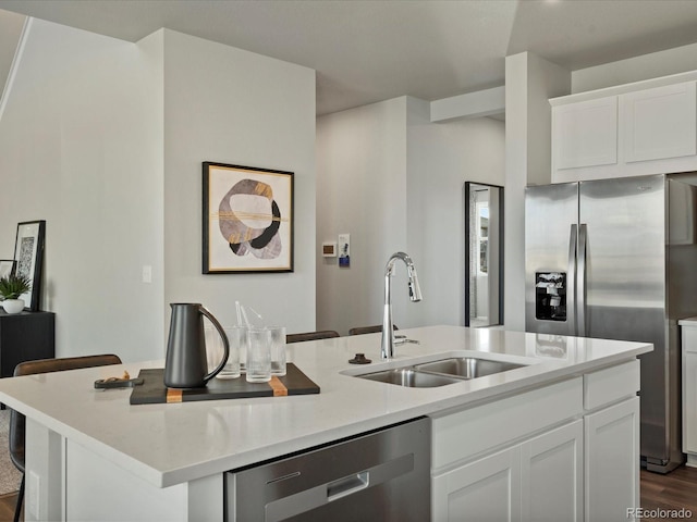 kitchen featuring a kitchen bar, sink, white cabinetry, appliances with stainless steel finishes, and an island with sink