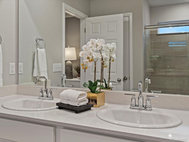 bathroom featuring a shower with shower door and vanity